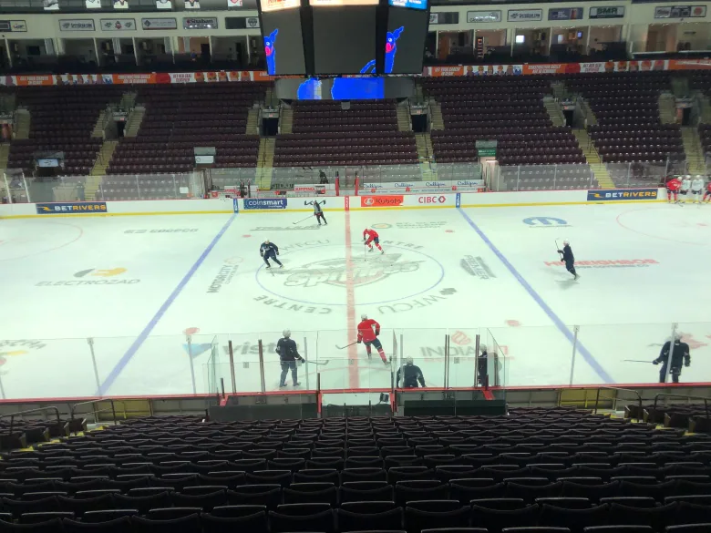 hockey players practice in a rink with empty stands.