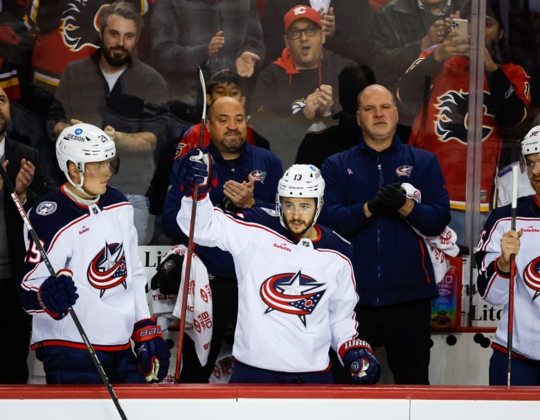 Columbus Blue Jackets forward Johnny Gaudreau, centre, waves to fans holding his stick in his right hand on his return to Calgary.