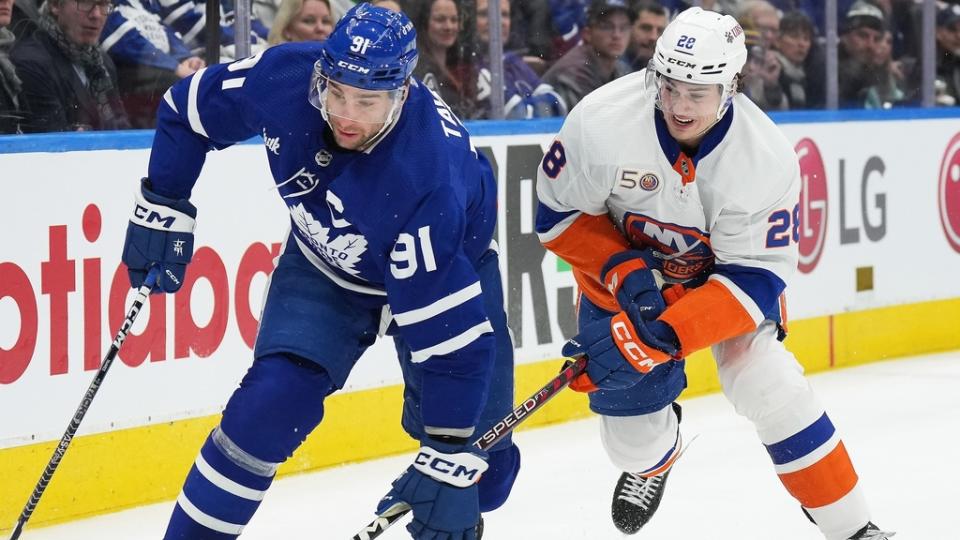 Jan 23, 2023; Toronto, Ontario, CAN; Toronto Maple Leafs center John Tavares (91) battles for the puck with New York Islanders defenseman Alexander Romanov (28) during the first period at Scotiabank Arena.