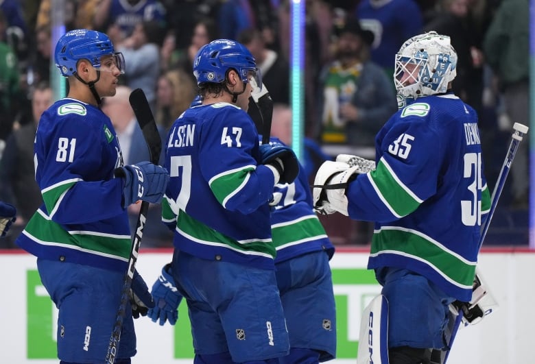 Vancouver Canucks' Dakota Joshua, from left to right, Noah Juulsen and goalie Thatcher Demko celebrate after Vancouver defeated the Dallas Stars.