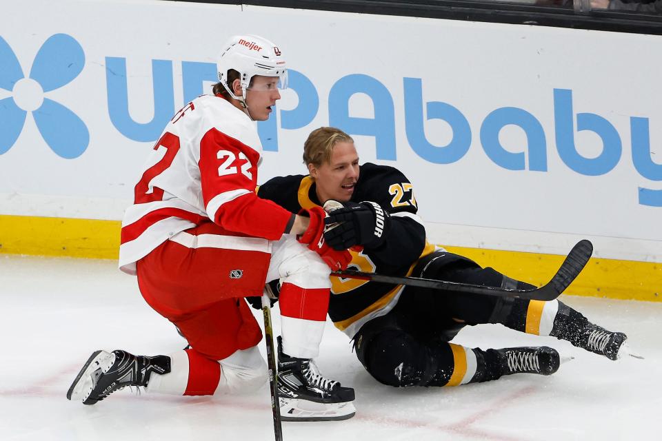 Detroit Red Wings right wing Matt Luff (22) dumps Boston Bruins defenseman Hampus Lindholm (27) during the first period at TD Garden in Boston on Thursday, Oct. 27, 2022.