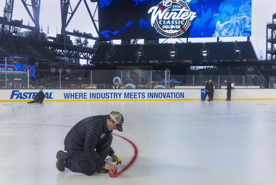 A member of the ice crew sprays water on a line so it will stay in place on the skating rink at the NHL Winter Classic ice skating rink at T-Mobile Park in Seattle Thursday, Dec. 28, 2023. The Seattle Kraken will fact the Las Vegas Golden Knights on Monday, Jan. 1, 2024. (Ellen M. Banner /The Seattle Times via AP)