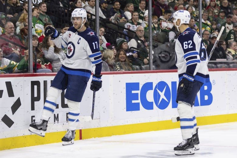 Two Winnipeg Jets players celebrate on the ice.