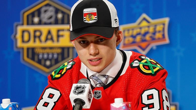 Men's hockey player, selected first overall in the NHL draft, wears a Chicago ball cap and jersey while addressing reporters.