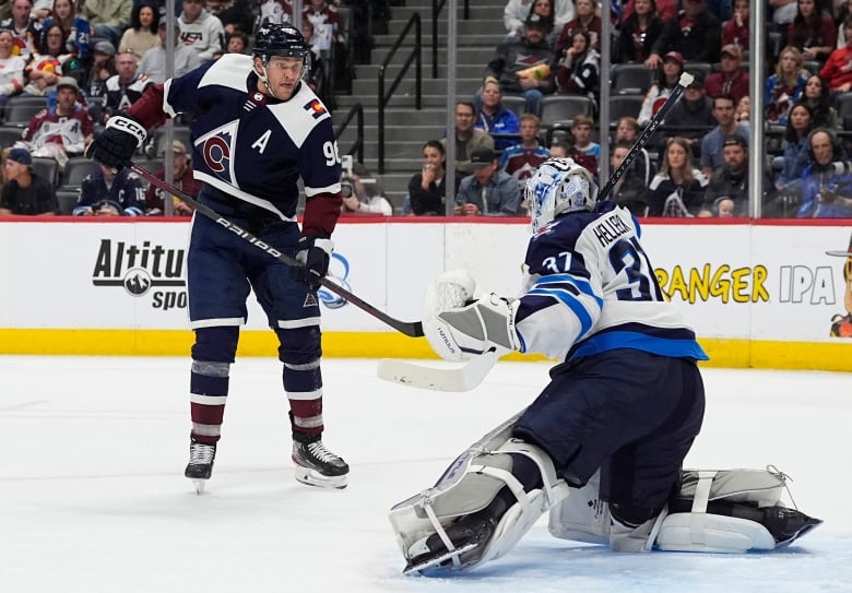 A goaltender stops a goal. Another hockey player stands in front of him.