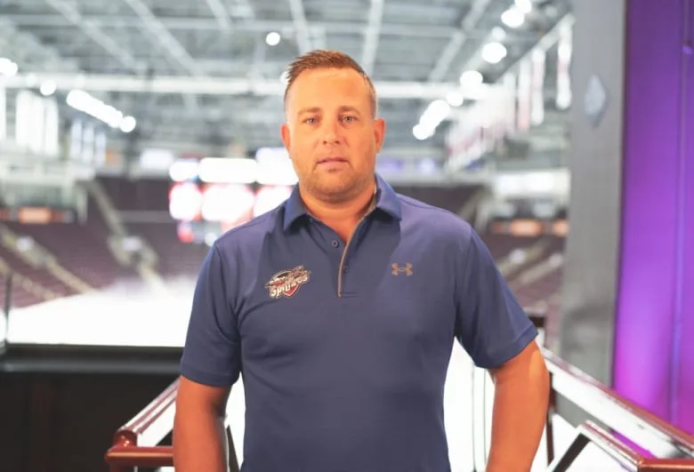 A man stands in front of an ice rink.