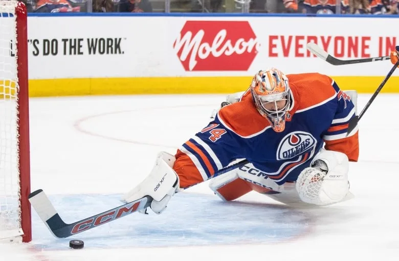 A hockey goalie makes a stick save.