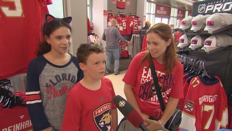 A woman stands beside a small boy and a girl. 