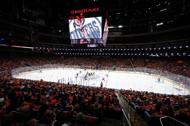 A view inside a packed stadium shows fans watching an ice hockey game.