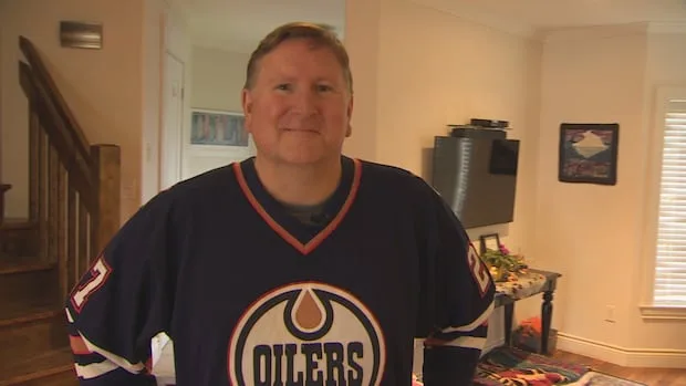 A smiling man wearing a retro Edmonton Oilers jersey