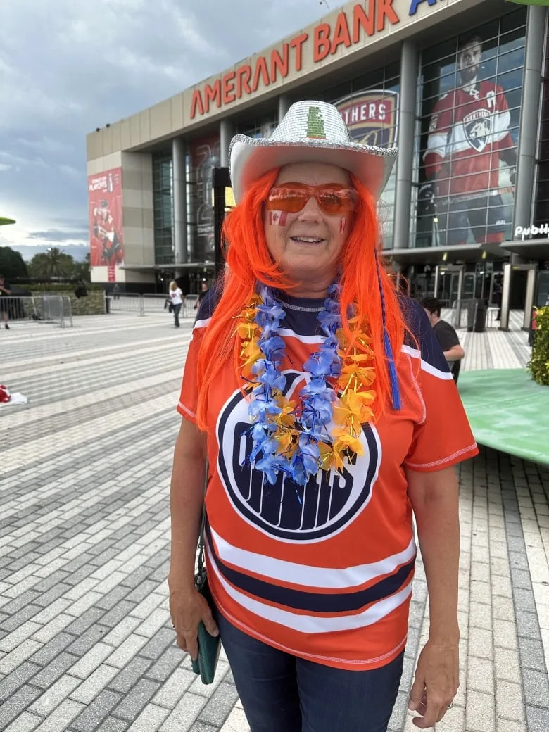 Woman in Oilers jersey and paraphernalia.