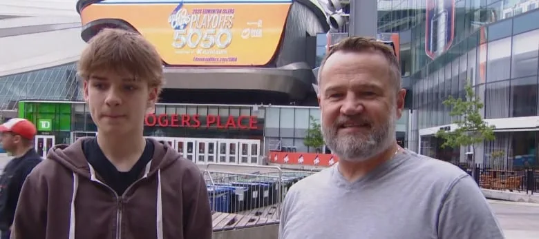 A man and a younger man stand to talk.