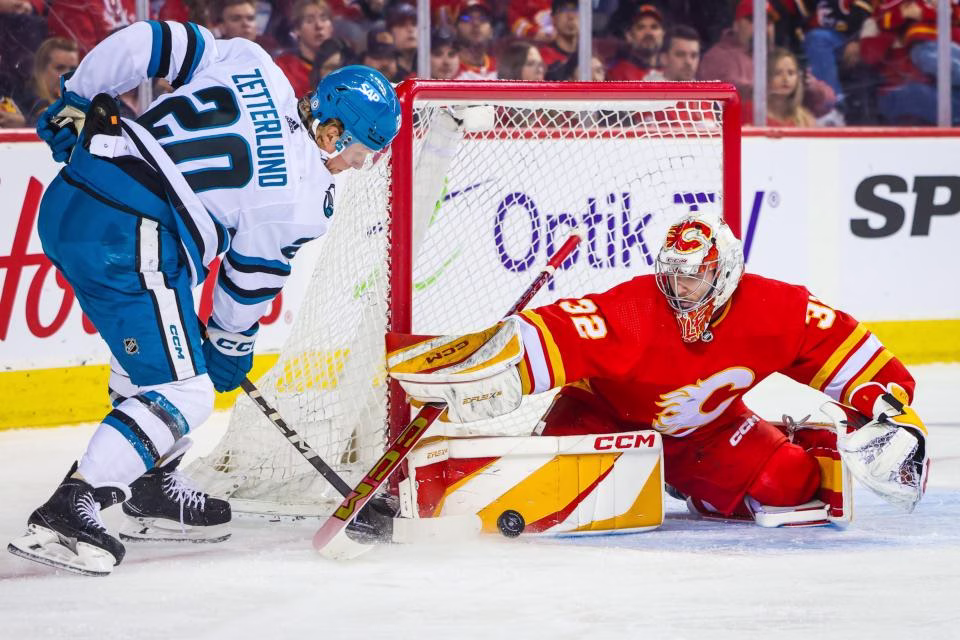 Apr 18, 2024; Calgary, Alberta, CAN; Calgary Flames goaltender Dustin Wolf (32) makes a save against San Jose Sharks left wing Fabian Zetterlund (20) during the first period at Scotiabank Saddledome. Mandatory Credit: Sergei Belski-Imagn Images