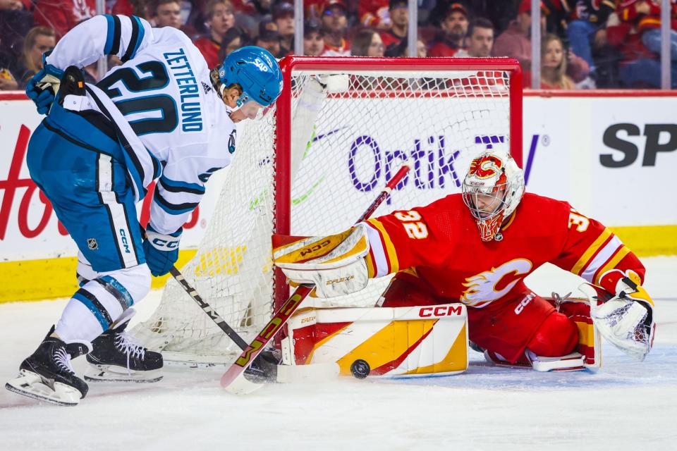 Apr 18, 2024; Calgary, Alberta, CAN; Calgary Flames goaltender Dustin Wolf (32) makes a save against San Jose Sharks left wing Fabian Zetterlund (20) during the first period at Scotiabank Saddledome. Mandatory Credit: Sergei Belski-Imagn Images