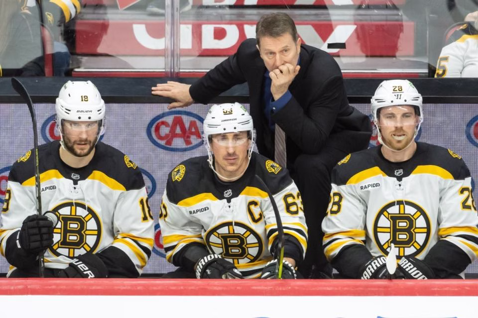 Boston Bruins interim coach Joe Sacco stands behind Pavel Zacha, Brad Marchand and Elias Lindholm in a Jan. 18 matchup.<p>Marc DesRosiers-Imagn Images</p>